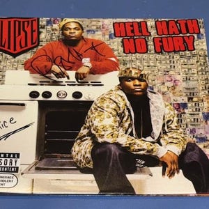 May include: Album cover for "Hell Hath No Fury" by Clipse, featuring two men in front of a stove. The cover includes the text "CLIPSE" and "HELL HATH NO FURY". The cover also has a parental advisory warning.