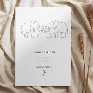 Op de afbeelding: Witte print met een lijntekening van drie olifanten. De tekst luidt "ESTHER CARLSEN", datum, gewicht (5,2 KG), lengte (32 CM) en de namen "MARK AND EMILY" met een hartsymbool.