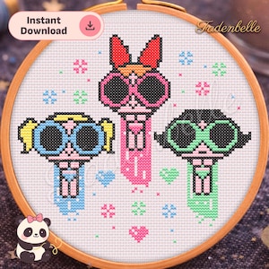 Puede incluir: Un patrón de punto de cruz con tres personajes de dibujos animados con gafas de sol grandes, cada uno con un esquema de color diferente: rosa, azul y verde. El diseño está dentro de un aro de bordado de madera. El texto "Instant Download" es visible.