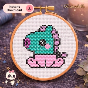 May include: A cross-stitch embroidery hoop featuring a cartoon character with a teal body, pink feet, and a purple head. The design is set against a white fabric, framed by a wooden hoop. The words "Instant Download" are in a pink oval.