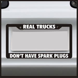 May include: Black license plate frame with white text that reads "REAL TRUCKS DON'T HAVE SPARK PLUGS".