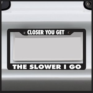Puede incluir: Marco de matrícula negro con texto blanco que dice "CLOSER YOU GET THE SLOWER I GO".