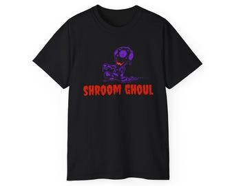 May include: A black short-sleeve t-shirt featuring a graphic of a purple mushroom-headed creature with a jagged orange mouth. Below the creature, the text SHROOM GHOUL is printed in a bold, distressed red font across the center of the chest.