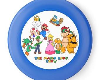 May include: A round blue flying disc featuring a white center graphic of various characters including Mario, Luigi, Princess Peach, Toad, Yoshi, Bowser, and others, with the text THE MARIO BROS. SHOW printed in colorful letters at the bottom.