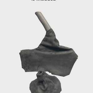 Könnte beinhalten: Dunkelgraues Wildleder-Autoteil, einschließlich eines Schaltsacks und einer Handbremsabdeckung. Der Text "Only The Uni Suede Part Is Included" ist oben im Bild aufgedruckt. Die Teile werden vor einem hellgrauen Hintergrund gezeigt.