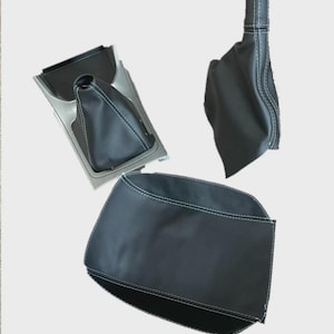 Könnte beinhalten: Schwarze Leder-Innenteile für Autos mit weißen Nähten. Das Bild zeigt eine Schalthebelmanschette, eine Schalthebelknaufabdeckung und eine Konsolenabdeckung. Der Text unten lautet "Nur das Lederteil ist enthalten."