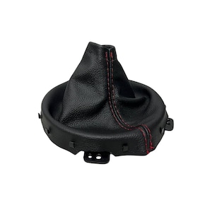 May include: A black leather shift boot with red stitching. The boot has a textured surface and a circular base with mounting tabs. The top of the boot is gathered and cone-shaped.