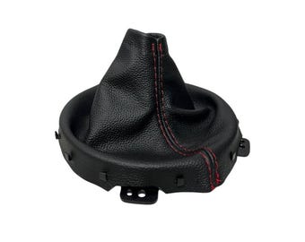 May include: A black leather shift boot with red stitching. The boot has a textured surface and a circular base with mounting tabs. The top of the boot is gathered and cone-shaped.