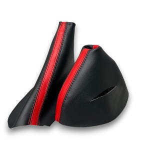 Peut inclure: Deux soufflets de levier de vitesse en cuir noir avec une bande rouge au centre. Les soufflets sont fabriqués en cuir texturé et sont posés sur un fond blanc.