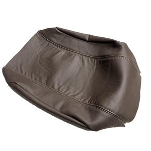 May include: A brown, leather-like bag with a curved shape. The bag has visible stitching along the seams and a smooth, slightly reflective surface. The bag appears to be empty and is set against a white background.
