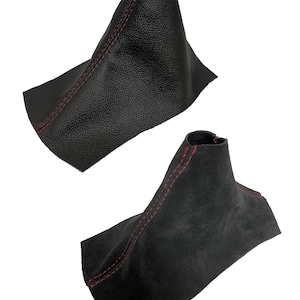 Peut inclure: Deux soufflets de levier de vitesse noirs avec des coutures rouges. L'un a un aspect cuir texturé, l'autre une texture de type daim. Les deux ont une forme conique avec une base large.