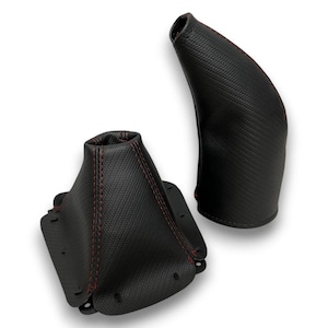 May include: Two black automotive shift boots with red stitching. The shift boots are made of a textured material and are designed to fit around the gear shift lever and the handbrake lever. The boots are shown against a white background.
