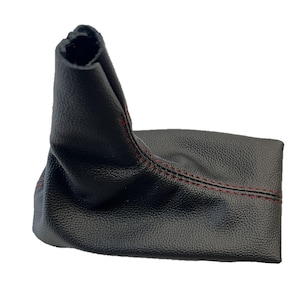 May include: Black leather shift boot with red stitching. The boot is made of a textured material and is designed to fit around a gear shift lever. The top of the boot is open, and the bottom is closed.