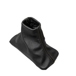 May include: A black leather shift boot with a textured surface. The boot has a rectangular base and a cylindrical top. Yellow stitching accents the seams.