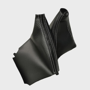 May include: Two black leather shift boots with white stitching. The boots are made of a textured leather material and are designed to fit over a vehicle's gear shift lever.