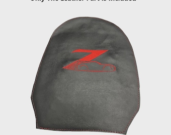 May include: A dark gray leather car seat cover with red stitching. The cover features a red embroidered design of the letter "Z" and a car silhouette. The text "Only The Leather Part Is Included" is at the top.