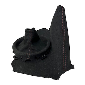 Peut inclure: Un soufflet de levier de vitesse et une housse de frein à main noirs perforés avec des coutures rouges. Le soufflet de levier de vitesse possède une base de montage circulaire en plastique, tandis que la housse de frein à main est allongée.