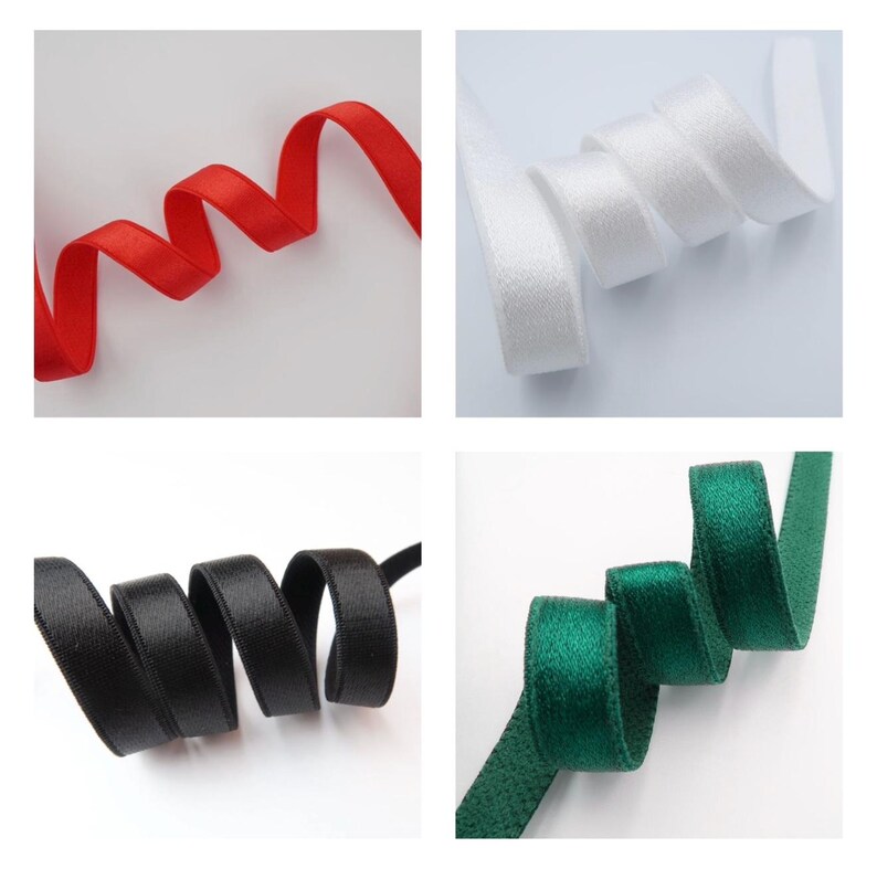May include: Four samples of satin ribbon in red, white, black, and green. Each ribbon is curled and displayed against a white background. The ribbons are smooth and have a slight sheen, suggesting they are made of a high-quality material.