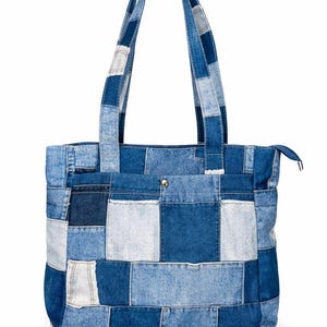 May include: A denim tote bag with a patchwork design. The bag features a variety of blue denim patches, creating a unique and textured appearance. It has two handles and a zipper closure, offering a stylish and functional accessory.