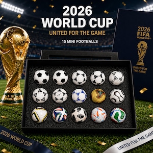 Op de afbeelding: Een display van 15 mini-voetballen in een zwarte doos, met een gouden trofee en een marineblauwe doos met de tekst "2026 FIFA WORLD CUP". De tekst "2026 WORLD CUP" en "UNITED FOR THE GAME" zijn ook zichtbaar.