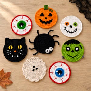 Puede incluir: Un conjunto de ocho posavasos redondos de ganchillo con diseños de Halloween que incluyen una calabaza, un gato negro, una araña, un monstruo verde, una calavera blanca, dos globos oculares con venas rojas y un posavasos beige festoneado.