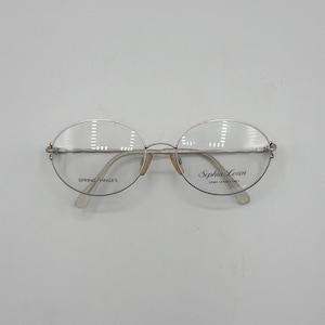 May include: Silver oval eyeglasses with clear demo lenses. The frames have a delicate design, with the text "Sophia Loren" and "Spring Hinges". The glasses have a classic, elegant style.