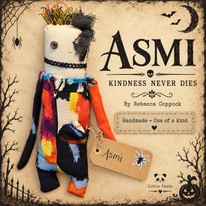 May include: A fabric doll with a cream-colored head, a single black button eye, and multi-colored hair. It wears a black, orange, and blue patterned jumpsuit with a zipper and a small pocket containing a tiny white figure. A brown tag reads Asmi.