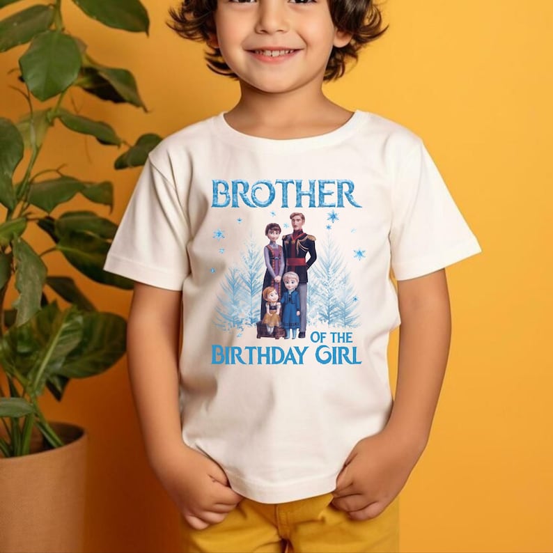 May include: Cream-coloured t-shirt with a graphic of characters from the film "Frozen" and the text "BROTHER OF THE BIRTHDAY GIRL" in blue. The shirt is being worn by a child.