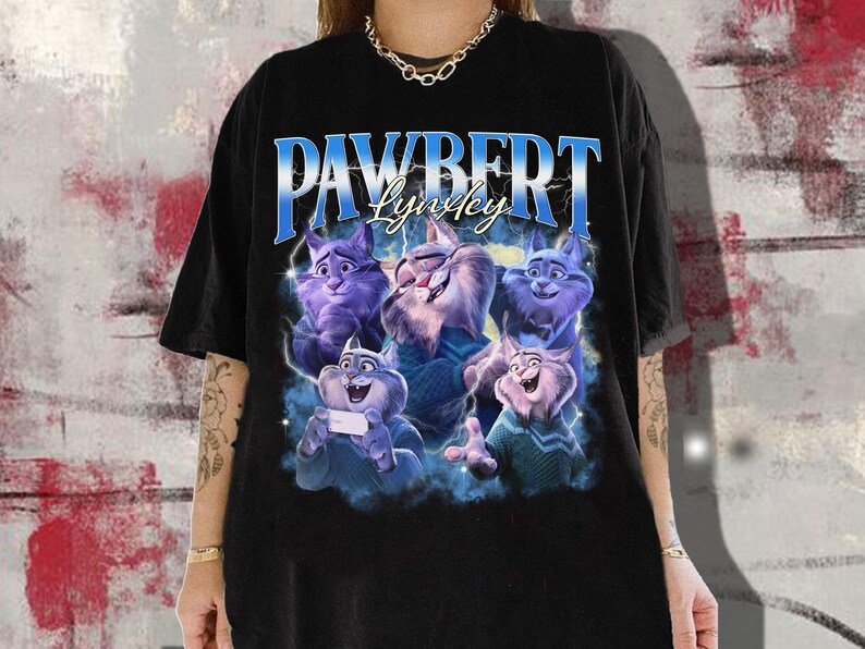 Op de afbeelding: Zwart t-shirt met een afbeelding van cartoonkatten en de tekst "PAWBERT Lynkey" in blauw en wit. De katten zijn in tinten paars, blauw en wit. Het shirt heeft een casual stijl.
