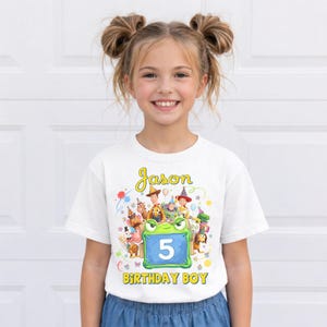 Pu&ograve; includere: T-shirt bianca con una grafica colorata con personaggi dei cartoni animati e il nome "Jason". Il numero "5" &egrave; visualizzato su uno sfondo blu, con le parole "BIRTHDAY BOY" sotto. Un design divertente e festoso.