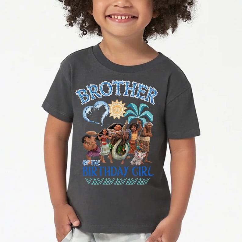 Peut inclure: Un t-shirt gris fonc&eacute; &agrave; manches courtes avec une impression graphique portant le texte BROTHER OF THE BIRTHDAY GIRL en bleu. Le motif comprend des illustrations de personnages du film Moana, un soleil, un palmier et une vague en forme de c&oelig;ur.