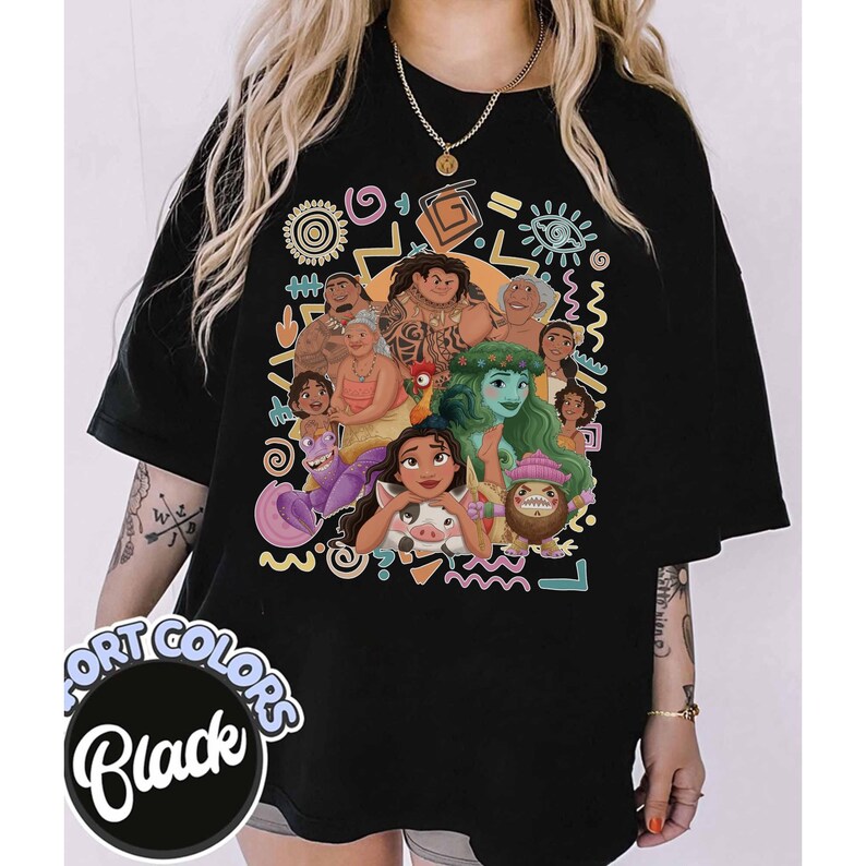 May include: A black t-shirt featuring a colorful graphic print of various animated characters from the movie Moana, including Moana, Maui, Pua, Heihei, and Tamatoa, surrounded by abstract shapes and symbols. A circular label reads Fort Colors Black.