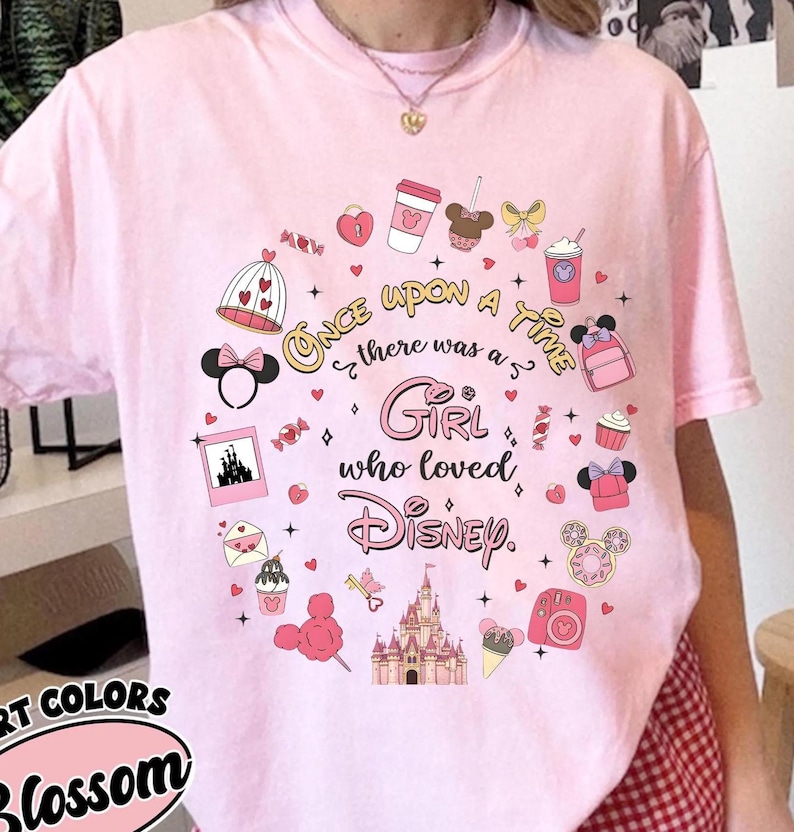 Puede incluir: Camiseta rosa claro con un dise&ntilde;o de Disney. El dise&ntilde;o incluye un castillo, orejas de Minnie Mouse y el texto "Once Upon a Time there was a Girl who loved Disney."