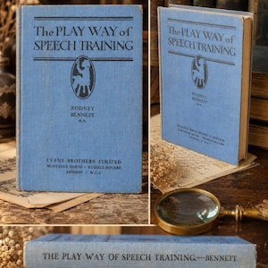 May include: A light blue hardcover book titled The Play Way of Speech Training by Rodney Bennett, M.A., published by Evans Brothers Limited. The cover features black text and a central oval illustration of a person sitting on a stool.