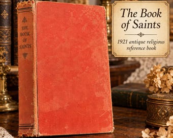 May include: An antique red hardcover book titled The Book of Saints, featuring a worn fabric texture on the cover and spine. The spine displays the title in black text with decorative flourishes. The book stands upright on a wooden surface.