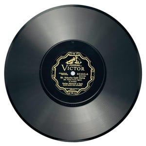 May include: A vintage black vinyl record with a gold and black label. The label reads "Victor" and includes the title "Mr. Vokurka Opět Doma" and the artist "Vaclav Albrecht a Spol". The record is a 78 RPM.