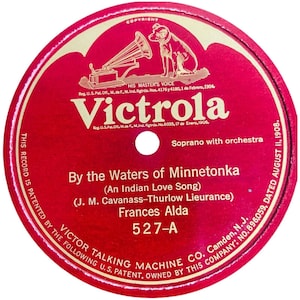 May include: A circular red Victrola phonograph record label featuring gold text and graphics. The label displays the His Master's Voice logo, the title By the Waters of Minnetonka, the artist Frances Alda, and the Victor Talking Machine Co. details.