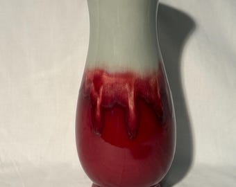 May include: A ceramic vase with a two-tone design. The top portion is a light gray, transitioning to a deep red with a glossy finish on the lower half. The vase has a flared top and a rounded body.