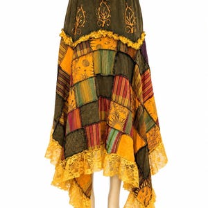 Puede incluir: Una falda de patchwork con cintura verde oliva, motivos de hojas bordados y cordón ajustable. La falda está compuesta por varios paneles cuadrados en tonos amarillo, naranja y verde, decorados con encaje a lo largo del dobladillo.