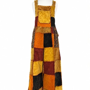 May include: A pair of patchwork dungarees featuring a square bib pocket and wide legs. The garment is constructed from rectangular fabric panels in shades of mustard yellow, deep burgundy, and black, with some sections displaying a subtle floral print.