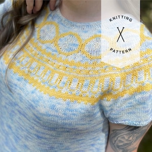 May include: A knitted top with short sleeves in a light blue and yellow color scheme. The top features a geometric pattern around the neckline. The text "Knitting Pattern" is visible in the image.