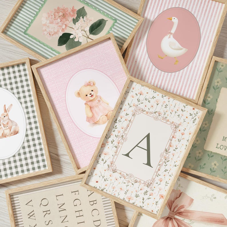 May include: A selection of framed art prints with diverse designs. The prints showcase illustrations of a teddy bear, a goose, flowers, and an initial. The frames are light wood, and the prints have pastel colour schemes.