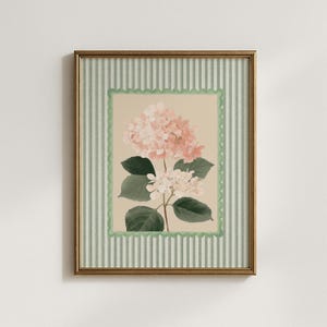 May include: A framed floral print of a hydrangea. The artwork features pink and white flowers, green leaves, and a beige background. It is framed with a green scalloped border and a striped green and white frame. The frame is gold.