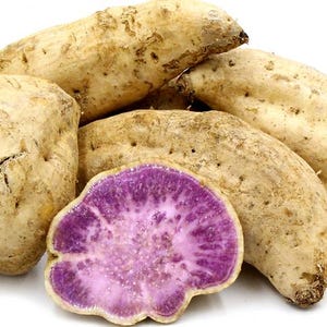 May include: A collection of sweet potatoes, some whole and others cut open to reveal a vibrant purple interior. The potatoes have a light brown skin with a slightly rough texture, and are arranged on a white background.