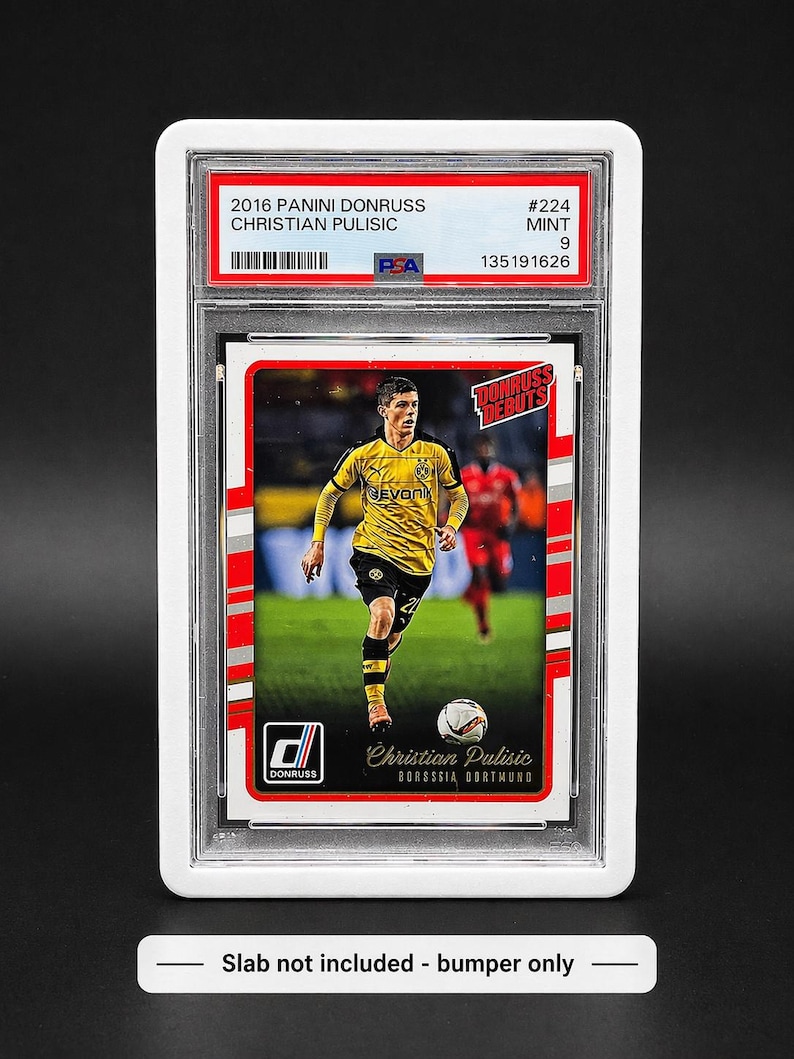 May include: A Panini Donruss trading card featuring Christian Pulisic in a yellow and black Borussia Dortmund uniform. The card is graded MINT 9 by PSA and includes the text "2016 PANINI DONRUSS CHRISTIAN PULISIC". The card is encased in a protective holder.
