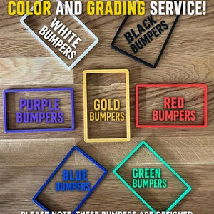 May include: Image of colored bumpers for graded cards. The bumpers are in white, black, purple, gold, red, blue, and green. Text on the bumpers reads "WHITE BUMPERS", "BLACK BUMPERS", "PURPLE BUMPERS", "GOLD BUMPERS", "RED BUMPERS", "BLUE BUMPERS", and "GREEN BUMPERS".