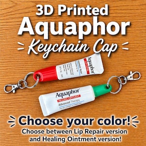 May include: 3D-printed Aquaphor keychain caps in red and green. The image shows two small tubes of Aquaphor, one with a red cap and the other with a green cap, attached to keychains. Text on the image reads "Choose your color!" and "Lip Repair version and Healing Ointment version!"