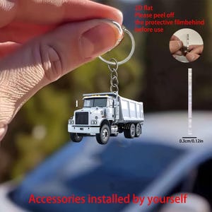 May include: A 2D flat white dump truck keychain with a silver metal ring and chain. The keychain has a thickness of 0.12 inches. Text on the image reads: 2D flat, Please peel off the protective film behind before use, Accessories installed by yourself.
