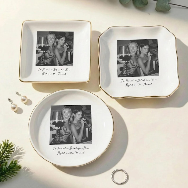 May include: A set of three white ceramic trinket dishes with gold rims. Each dish features a black and white photo of two women and the text "I'd Punch a Bitch for You Right in the Throat". The dishes are square, scalloped, and round.