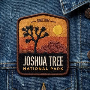May include: Embroidered patch featuring a Joshua Tree National Park landscape with a Joshua tree, mountains, and a sun. The patch has the text "JOSHUA TREE NATIONAL PARK" and "SINCE 1994" on a denim jacket.